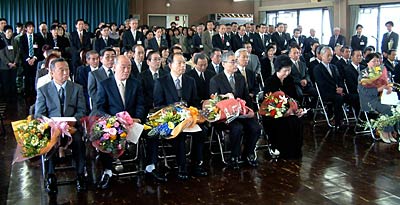 花束を手に席を並べる退職者