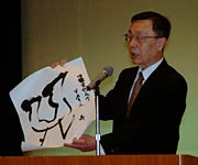  退任のあいさつで「鼎」の書を広げる中野副市長