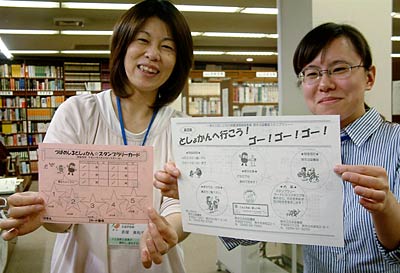 スタンプラリーカードとちらしを手に燕市3図書館スタンプラリーへの参加を呼びかける図書館職員