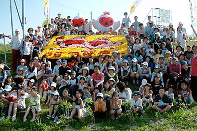 新潟国体のキャラクター「トッキッキ」をデザインした花絵を囲み、参加者とトッキッキの着ぐるみで記念撮影