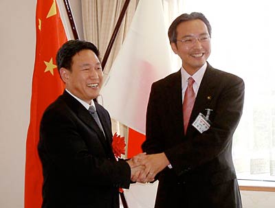 五星旗と日の丸を背に握手する鄂州市経済代表団の李団長(左)と国定三条市長(右)