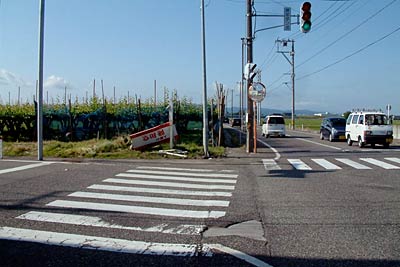 死亡事故のあった三条市代官島の交差点、写真付近には入江さんの車がぶつかったと思われる壊れた看板やポールが