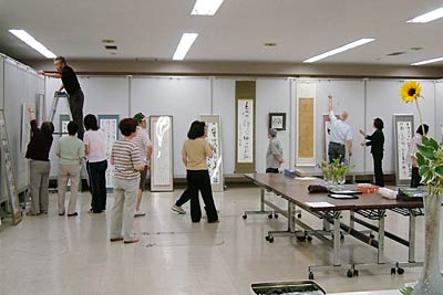 20日から22日まで三条市中央公民館で開かれている三條蘭亭会第21回書道展の展示作業