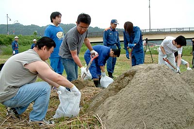 五十嵐川沿線企業から17人が参加して土のうの作り方、摘み方の訓練