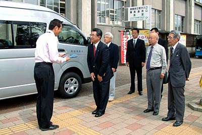 寄付したワンボックスカーの前で国定三条市長(いちばん左)にキーや車検証を渡す三条南ロータリークラブの坂本会長(左から2番目)