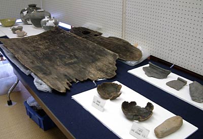 栄地区遺跡のテーマ展示(井戸枠につかわれた木や中世の食器)