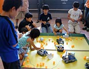 練習用フィールドでロボットを試運転する子どもたち