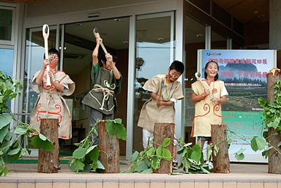 3日、テープカットの代わりに大浦小6年生が復元した縄文時代の石斧で植物のつるを切って開場した遺跡発掘調査速報巡回展2008下田会場展