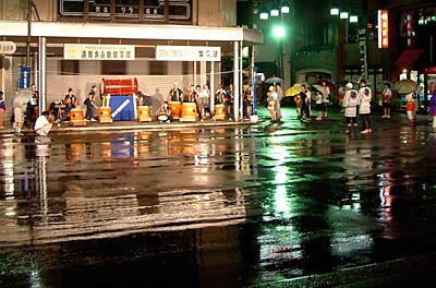 降りやまない雨のなか、アーケードの下で太鼓演奏する吉田太鼓龍神会