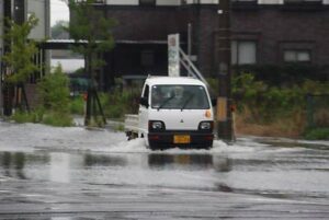28日午前5時40分、燕市井土巻2地内の冠水した道路を水しぶきを上げて走る軽トラック