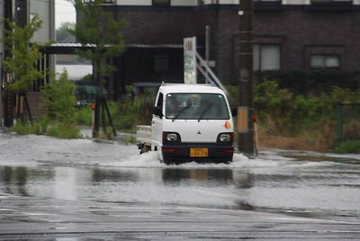 28日午前5時40分、燕市井土巻2地内の冠水した道路を水しぶきを上げて走る軽トラック