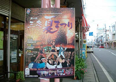 ポスターや紅白幕が下がり、三条夏まつりが間近いことを知らせる三条市の商店街