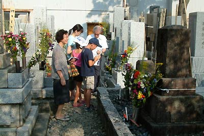 =墓参りの13日夕方、三条市内の寺院の墓地で墓参りし、手を合わせる