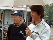 プロジェクト指導者の畦地健雄さんと並んで観戦する哀川さん