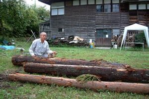 会場の庭月テラ小屋で13日に雨宮氏がはつる丸太と馬場会長