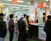赤いゲートを設置した年賀はがき臨時窓口に来店客の列