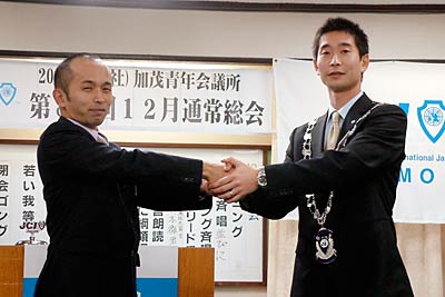 丸山理事長（左）と握手する阿部次年度理事長（右）