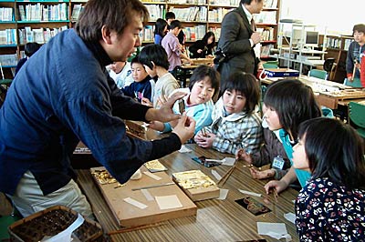 三条市立西鱈田小学校4年生に三条仏壇の製造体験を指導する三条・燕・西蒲仏壇組合の職人、金ぱくの説明を聞く児童