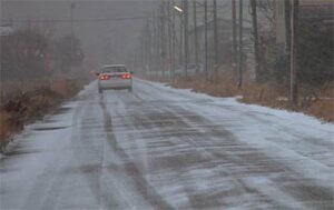 雪で景色がかすみ、道路をうっすらと雪が覆う三条市須戸地内