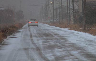 雪で景色がかすみ、道路をうっすらと雪が覆う三条市須戸地内