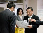 国定市長に向かって寄付の目録を読み上げる角利産業の加藤社長