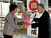小池加茂市長(右)から花束を受ける100万人目の入館者、小出さん