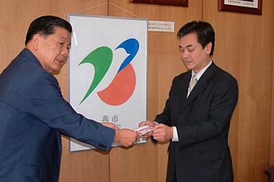  小林燕市長(左)に52,000円余りを寄付する浅野(株)ホクエツ社長(右)