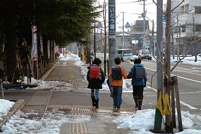 三条市役所前通りを防寒着を手に学校から帰る小学生