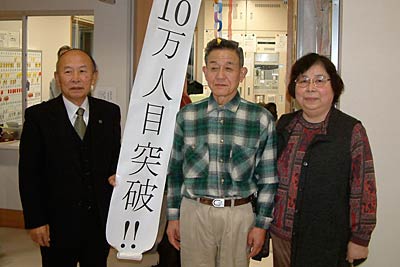 「しらさぎ荘」10万人目となった野水さん夫婦と(右)と佐藤和夫副市長(左)