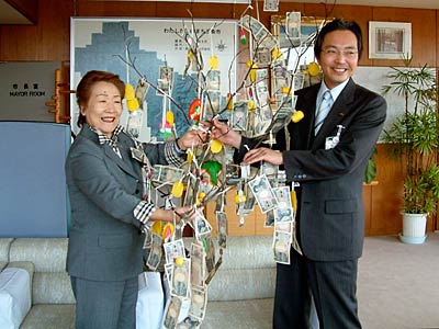 国定市長に「スナックマンマ」の来店客の善意が下がった繭玉飾りを手渡す「マンマ」経営の五十嵐さん