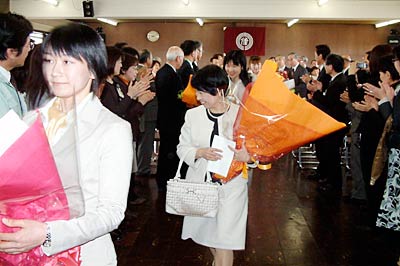 職員の拍手に送られて退場する退職者