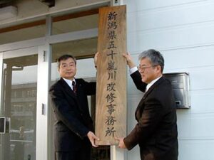 県三条地域振興局五十嵐川改修事務所の看板を取り外す大宮局長(左)と常山所長(右)