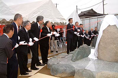 紅白のひもを引いて記念碑の除幕