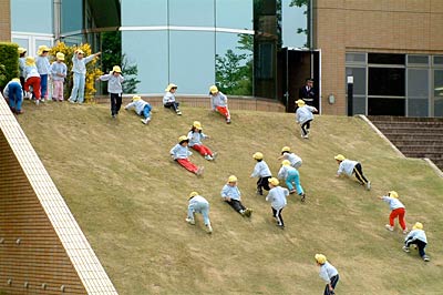 芝生の斜面を滑って遊ぶ園児たち