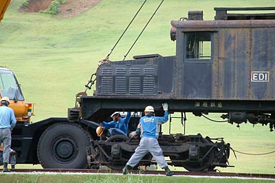 展示場所でクレーンでつり上げて車輪部分に乗せられる車両本体