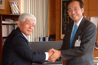 国定市長から辞令書を受け取ってがっちり握手する吉田副市長