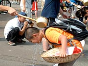 ひしゃくで頭に水をかけてもらう子どもたち