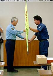 八幡燕署長から交通安全「旗」を受ける玉木安全運転管理者