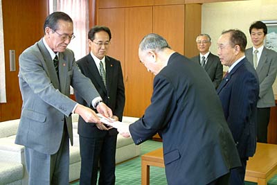 小池市長に車いす8台の目録を手渡す加茂信用金庫の梁取理事長ら