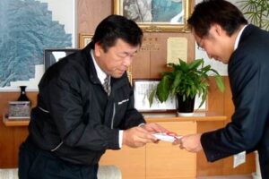 国定三条市長(右)に三条東公民館に設置、寄付したペレットストーブの目録を手渡す新潟エコエネルギーの柳原社長(左)