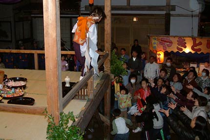 杵樹の舞で伶人がまく供物に手を伸ばす参拝客