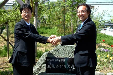 除幕した記念碑の前で握手する鈴木燕市長(左)と国定三条市長(右)