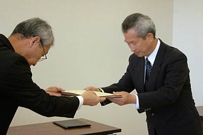 田浦選管委員長(左)から佐藤町長代理の佐野後援会長(右)に当選証書を手渡す