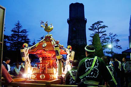 燕市のシンボル、水道塔のシルエットをバックに燕市文化センターで24時間耐久みこしに出発の準備する燕1000人みこし
