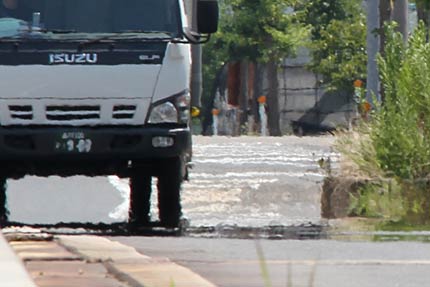 燕市井土巻地内、逃げ水が見え、景色が揺れるアスファルトの道路