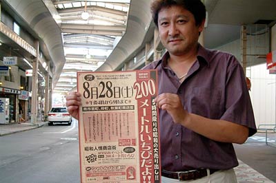 商店街でちらしを手に200メートルいちびへの来場を呼びかける小黒実行委員長