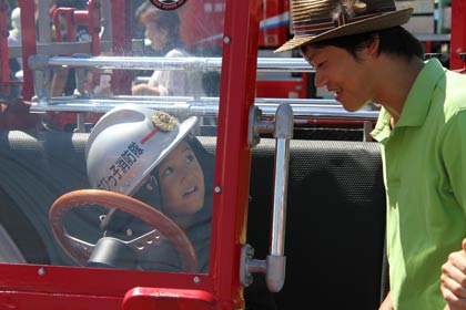 子ども用の消防車のハンドルを握ってすっかり気分は消防士