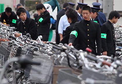 駐輪場の自転車の防犯度を点検する高校生