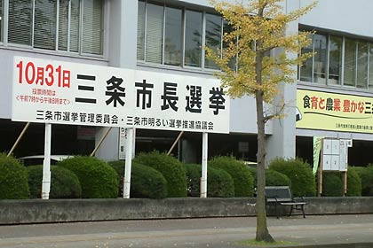 三条市役所前の三条市長選への投票を呼びかける看板とポスター掲示板