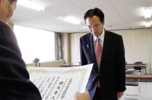 三条市選挙管理委員会の高野委員長から当選証書を受ける国定市長